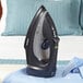 A black Conair Cord-Keeper steam iron on a shirt.