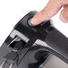 A hand pressing the black button on a Conair Cord-Keeper Steam Iron.