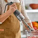 A handheld Robot Coupe MMP190VV Combi Mini 8-inch variable speed immersion blender with a 7-inch whisk attachment being used in a kitchen.