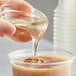 A person pouring Bossen cane sugar syrup into a glass of brown liquid.