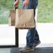 A man holding two Sabert tamper-evident brown paper bags.