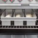 A Chicago Metallic aluminized steel bread loaf pan with three loaves of bread in it sitting in an oven.