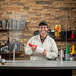 A man standing behind a Tablecraft clear acrylic countertop safety shield on a convenience store counter.