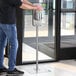 A man using a Steril-Sil hand sanitizer floor stand in a corporate office cafeteria.