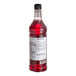 A close up of a Monin Premium Dragon Fruit flavoring syrup bottle filled with red liquid.