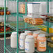 A large green wire shelving unit used for storage in a commercial kitchen or pantry.