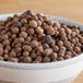 A bowl of Regal Whole Allspice on a wooden table.