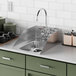 A Waterloo stainless steel drop-in sink with a faucet and side splashes on a green counter.