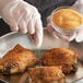 A person in gloves sprinkling Regal roasted garlic granules on chicken.