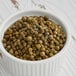 A bowl of Regal green peppercorns on a wooden table.