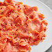 A plate of smoked salmon with pink peppercorns and lemon on a table.