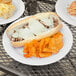 A Carlisle white melamine plate with a sandwich, cheese, and potato chips on it.