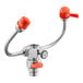 An orange and chrome metal faucet with two handles and an eyewash station attachment.