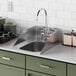 A Waterloo stainless steel drop-in sink with faucets and side splashes in a green counter and cabinet.