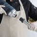 A person in a chef's uniform and gloves using an AvaMix heavy-duty metal blending shaft.