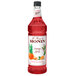 A bottle of Monin Premium Orange Spritz flavoring syrup with red liquid inside.