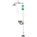 A close-up of a polished chrome Guardian Equipment safety station with a green sign above a shower head.