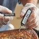A digital pocket probe thermometer being used to measure the temperature of cooked meat.