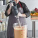 A man using an AvaMix heavy-duty immersion blender to mix a liquid.