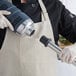 A person in a chef's uniform using an AvaMix heavy-duty immersion blender with a metal tube attachment.