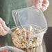 A person in gloves holding a Choice clear plastic deli container of pasta and vegetables.