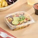 A clear 8 oz. RPET hinged deli container filled with a colorful bean and corn salad, shown with a secure lid.