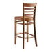 A Lancaster Table & Seating wooden ladder back bar stool with a vintage wood seat and back.