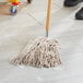 A person using a Lavex Natural Cotton wet mop to clean a floor.