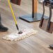 A person using a Choice natural cotton dry mop on a wood floor.