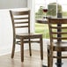 A Lancaster Table & Seating wooden ladder back chair with a vintage wood seat on a table in a restaurant dining area.