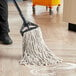 A person using a Choice Natural Cotton wet mop with a handle to clean a floor.