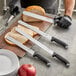 A person using a Schraf serrated knife to slice bread on a cutting board.