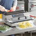 A woman using a Galaxy vacuum packaging machine to seal tomatoes.