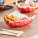 A red oval plastic basket with chicken strips and sauce.