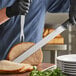 A person using a Schraf slicing knife to cut meat.