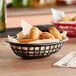 A black oval plastic fast food basket filled with food on a table.