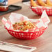A red GET round plastic fast food basket filled with food on a table in a pizza parlor.