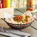 A round black plastic fast food basket filled with food on a table.