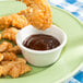 A plate of chicken strips and french fries with a bowl of Thunder Group Bone Smooth Melamine Ramekin on the table.