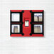 A white brick wall with a red Hatco Flav-R 2-Go pickup locker with black frames and windows.