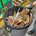 A man holding wooden planks in a trash can lined with a Lavex Pro heavy-duty black trash bag.