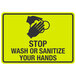 A yellow and black aluminum sign with black text and a hand washing symbol that says "Stop / Wash Or Sanitize Your Hands"