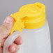 A person holding a Tablecraft dispenser jar with a yellow lid.