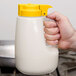 A hand using a yellow Tablecraft dispenser to pour.