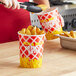 A person holding a Choice red and white paper cup filled with french fries.