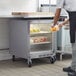 A man in a white apron putting food into a Beverage-Air undercounter refrigerator.