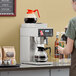 A woman making coffee in an Estella Caffe automatic coffee maker with decanter warmers.