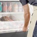 A man in an apron opening a black Avantco horizontal air curtain merchandiser.