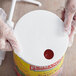 A person in gloves snaps a Tablecraft snap on adapter lid onto a container of sauce.