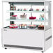 A Turbo Air white refrigerated bakery display case with three tiers of cakes and desserts.